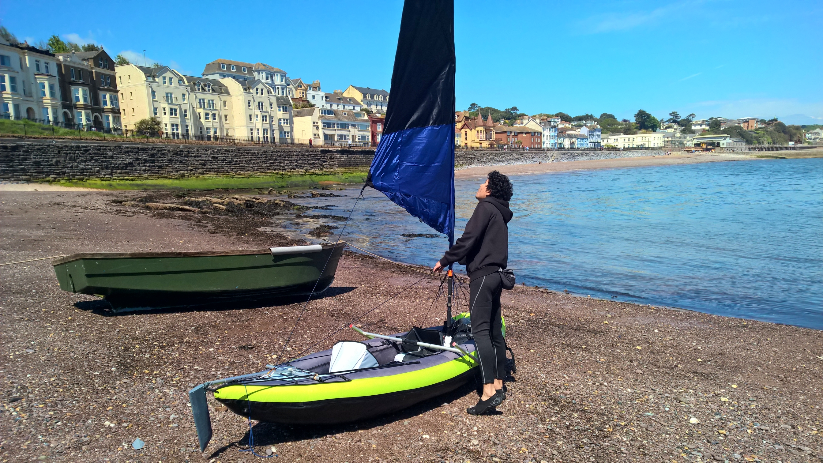 man building a sailing kit in a kayak in the beach